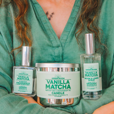 Woman in a green top holding the Vanilla Matcha candle, cologne and room spray