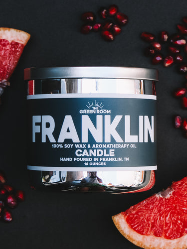 Franklin 100% soy wax candle with grapefruit slices and pomegranate seeds on a black background
