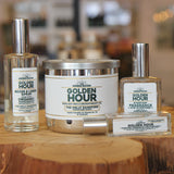 Three fragrance products from The Golden Hour line are displayed on a rustic wooden slice stand in a store setting. 