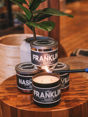 Lighting a Franklin candle, with Nashville candles stacked on a wooden table