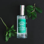 Spearmint & Basil room spray with fresh spearmint and basil leaves on a black background