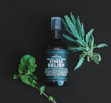 Stress Relief organic face serum with fresh lavender and mint sprigs on a black background
