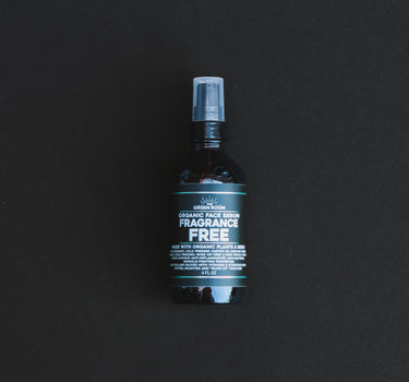 Fragrance Free organic face serum in an amber glass bottle on a black background
