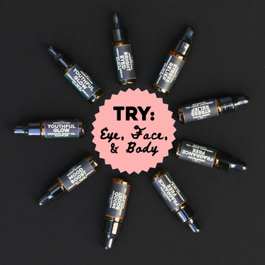 The Green Room Organic Skincare Samplers: 5 ml amber dropper vials of face serum, eye serum and body oil (Bright Eyed Organic Eye Serum · Youthful Glow Organic Face Serum · Mood Boost Organic Face Serum · Stress Relief Organic Face Serum · Fragrance Free Organic Face Serum · Youthful Glow Organic Body Oil · Mood Boost Organic Body Oil · Stress Relief Organic Body Oil · Fragrance Free Organic Body Oil) arranged in a ring on black, around a pink badge that reads Try: Eye, Face & Body.