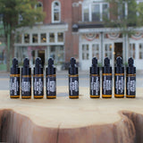 The Green Room 9 PC Organic Skincare Sampler Collection: all nine 5 ml amber dropper vials of face serum, eye serum and body oil lined up on a wood slab outside the shop on Main Street in Franklin, TN.